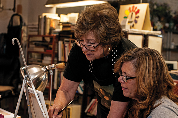 Capitol City Artists founder Judi Hooks offers advice to a student working in her studio.